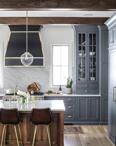 a kitchen with blue cabinets and marble counter tops