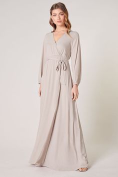 Warm and inviting, the Wholehearted Maxi Dress is a perfect combination of modest and sultry. Long balloon sleeves frame a surplice neckline separated by a tie at the waist, creating a forgiving faux wrap. The skirt maintains an airy and flowy shape that trails behind as you walk down the aisle. - Chiffon- Faux wrap- Keyhole- Elastic waist- Comes in 14 ColorsSize + Fit - Model is 5'9" and wearing size XS- Measurements taken from size S - Chest: 35"- Length: 63 1/4" Fabric Self: 100% PolyesterLin Modest Fitted V-neck Maxi Dress, Flowy V-neck Dress With Surplice Neckline For Date Night, Fall V-neck Belted Maxi Dress, Fitted V-neck Maxi Dress With Tie Waist, Formal Fall V-neck Wrap Dress, Flowy Wrap Dress For Date Night, Flowy Belted Wrap Dress With Surplice Neckline, V-neck Maxi Dress With Tie Waist, Chic Fall Maxi Dress With Surplice Neckline