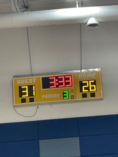 an electronic clock hanging from the ceiling in a gym