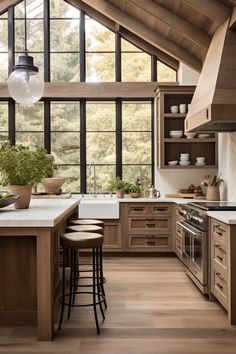 a kitchen with wooden floors and lots of counter space in the center, along with large windows