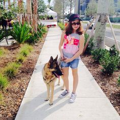 a girl is walking her dog down the sidewalk