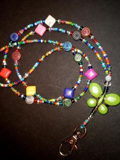 a colorful beaded lanyard with a butterfly charm and matching keychain on a black surface