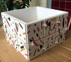 a white box with multicolored paint splattered on it sitting on top of a wooden table