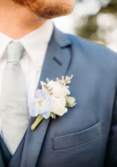 a man wearing a blue suit and flower boutonniere on his lapel