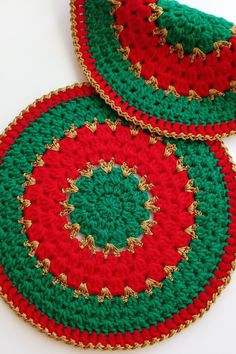 two red and green crocheted coasters sitting on top of a white table