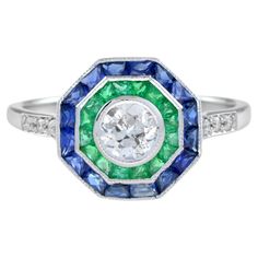 An incredibly stylish Art Deco target ring, set with a double halo clusters of gemstones – blue sapphire and emerald around a central old cut diamond. The diamonds are bright, displaying excellent flash and sparkle, while the sapphire and emerald have a great vivid color. Ring Information Style: Art-deco Metal: 18K White Gold Total weight: 2.93 g. (approx. total weight) Size: US7 (resizable) Center Gemstone Type: Diamond Shape: Old Cut Round Shape Average Color: H Average Clarity: SI Size: 4.5 m Blue Emerald Rings With Halo Setting, Blue Emerald Ring With Halo Setting, Blue Emerald Halo Setting Ring, Antique Emerald Engagement Ring, Target Ring, Double Halo Ring, Emerald Ring Engagement Diamond, Vintage Engagement Rings Sapphire, Vintage Sapphire