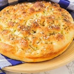 a freshly baked pizza sitting on top of a wooden plate next to a blue and white checkered towel