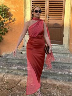 a woman in a red dress is standing outside