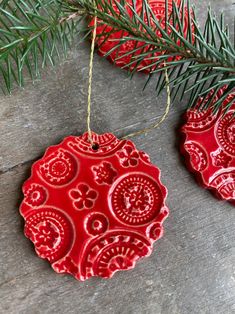 a red ornament hanging from a pine tree on top of a wooden table