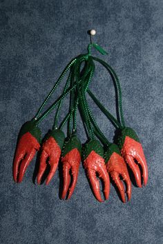 five red and green plastic claws hang from a hook on a blue carpeted surface