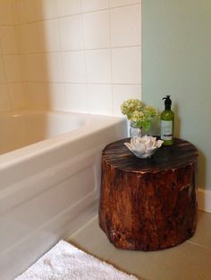 a wooden table with flowers and bottles on it next to a bathtub in a bathroom