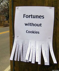 a sign posted on a telephone pole that says fortunes without cookies with strips of paper stuck to it