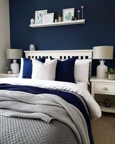 a bedroom with blue walls, white bedding and two lamps on the nightstands