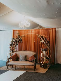 a couch sitting under a chandelier in front of a red drape covered wall