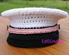 a close up of a knitted hat on a wooden table with grass in the background