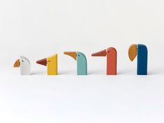 four different colored wooden birds standing in a row on a white surface with the word bird spelled out