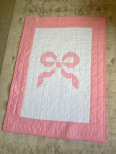 a pink and white quilt with a bow on it