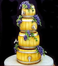 a three tiered cake decorated with grapes and wine barrels