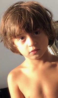 a shirtless boy with no shirt on is looking at the camera