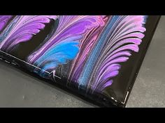 a black case with purple, blue and pink feathers painted on the inside of it