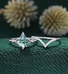 three different types of engagement rings with diamonds on green cloth and flowers in the background