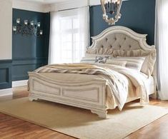 a large white bed sitting in a bedroom on top of a hard wood floor next to a chandelier