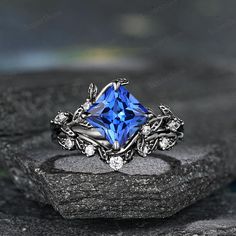 a blue diamond ring sitting on top of a black stone slab with white diamonds around it