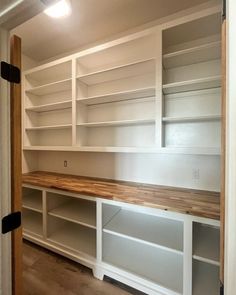 an empty room with white shelves and wood counter tops in the center, along with no doors or drawers