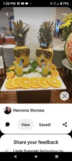 two pineapples are sitting on top of a table with orange slices and watermelon