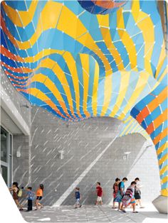 children are walking around in front of a large mural on the side of a building