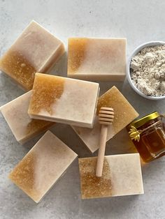 soaps and honey sit on a table next to a spoon