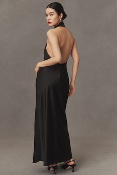 a woman in a long black dress is standing back to back with her hands on her hips