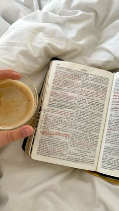 an open book and a cup of coffee on a bed