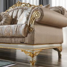 an ornate couch with gold trimmings and pillows on top of wooden flooring