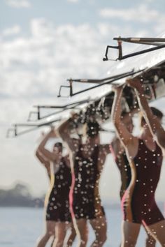 several women in swimsuits are carrying skis on their shoulders over their heads