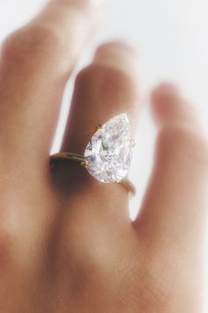 a woman's hand with a diamond ring on top of her finger, close up