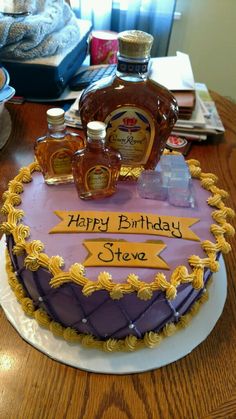 a birthday cake that is on top of a table with bottles of liquor and an empty bottle