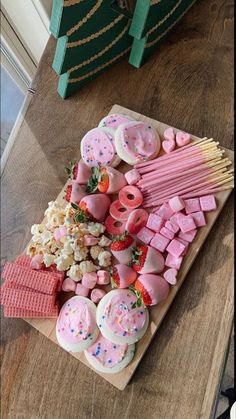 a wooden table topped with lots of pink and white desserts on top of it