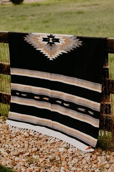 a black and white blanket sitting on top of a pile of rocks next to a fence