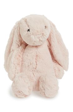 a pink stuffed rabbit sitting up against a white background