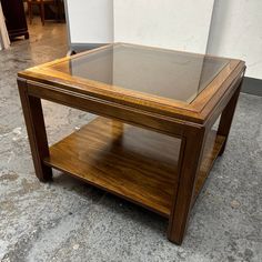 a wooden table with glass top sitting on the floor