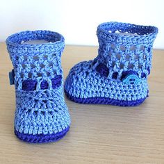 a pair of blue crocheted baby boots sitting on top of a wooden table