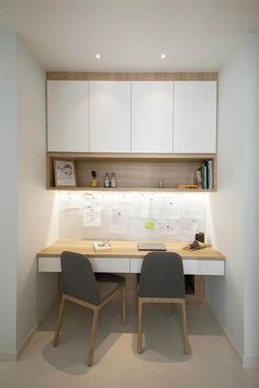 two chairs sitting at a desk in front of a white cabinet and shelves with papers on it