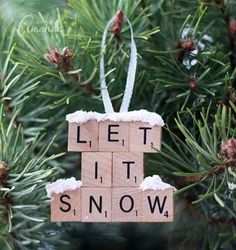 a wooden block ornament that says let it snow hanging from a pine tree