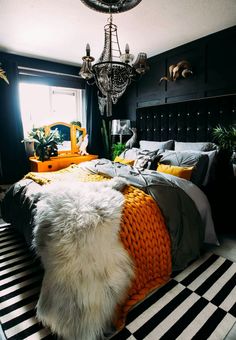 a bedroom with black walls, white and orange bedding and a chandelier hanging from the ceiling