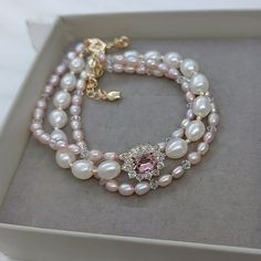 Material: Pink freshwater pearls, white freshwater pearls, cubic zirconia embellished oval settings with Swarovski antique pink crystals, small Swarovski crystal beads.  Size: The center pink stone is 6mm*8mm. The centerpiece is 1.1 cm*1.5 cm.  A. 16cm B. 17cm C. 18cm D. 19cm E. 20cm Please choose a size when you place the order. If you are not sure which size to choose, please leave a note to tell us your wrist size(without space). We will make the bracelet fit you.  Metal Color: Gold. 1920s Luxury, Alley Rose, Pink Pearl Jewelry, Blush Natural, Pink Pearl Bracelet, 1920s Jewelry, General Ideas, Freshwater Pearl Bracelet, Swarovski Crystal Beads