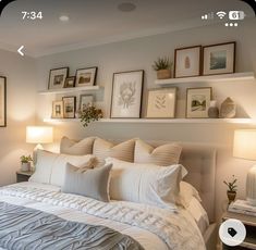 a white bed sitting in a bedroom next to two lamps and pictures on the wall