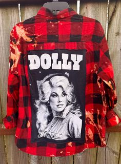 a red and black shirt with the words dolly on it, hanging up against a wooden fence