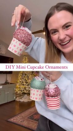 a woman holding up two cupcakes in front of her face with the words diy mini cupcake ornaments