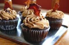 cupcakes with bacon on top sitting on a tray